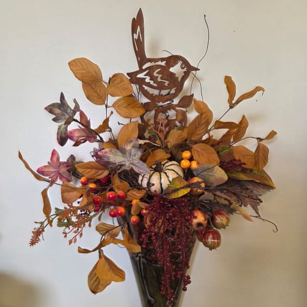 Autumn floral arrangement with faux leaves, berries, and pumpkins in a dark vase