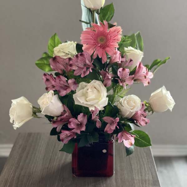 Pink and white roses with pink alstroemeria in a red glass vase