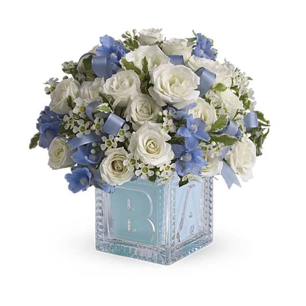 White rose and blue flower arrangement in a glass baby block cube vase with blue ribbon accents