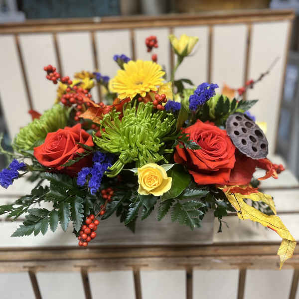 Colorful floral arrangement with red and yellow roses in a rectangular container