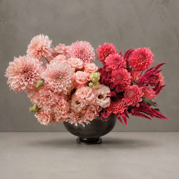 Pink and magenta dahlia arrangement in a black bowl vase