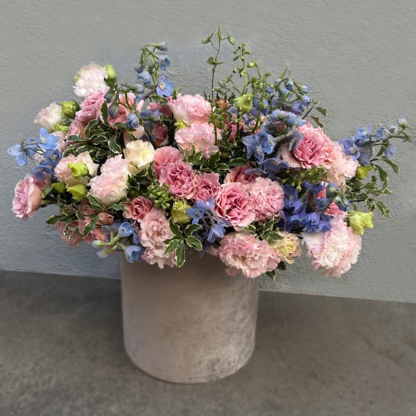 Pink and blue mixed flowers arranged in a round velvet vase