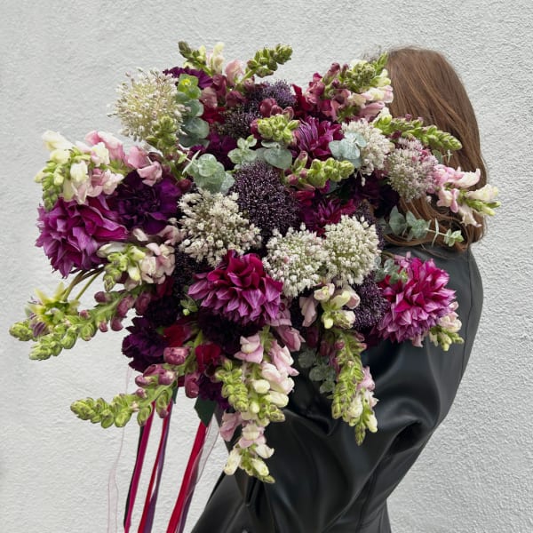 Large bouquet of purple, pink, and white flowers held by a person