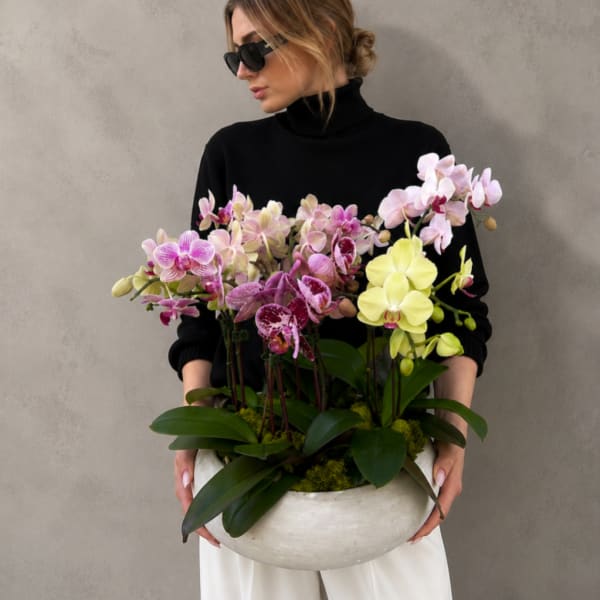 Woman holding a large bowl of pink and yellow orchids