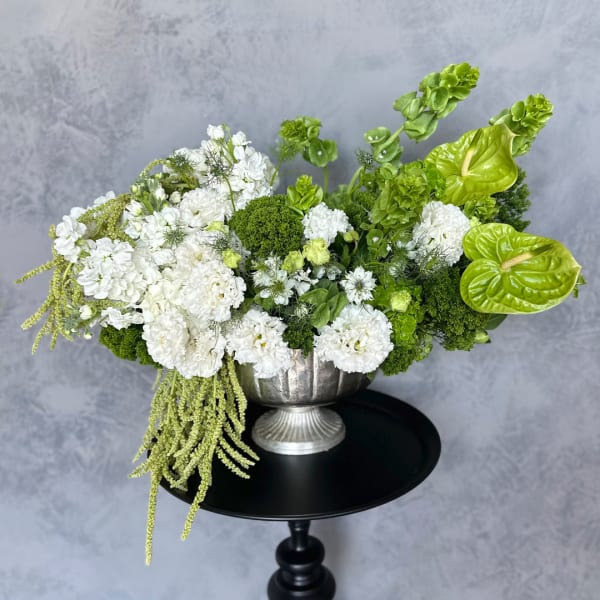 White and green floral arrangement in a silver pedestal vase