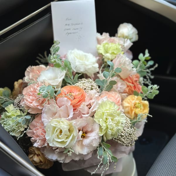 Pastel bouquet of mixed flowers in a black box with a card