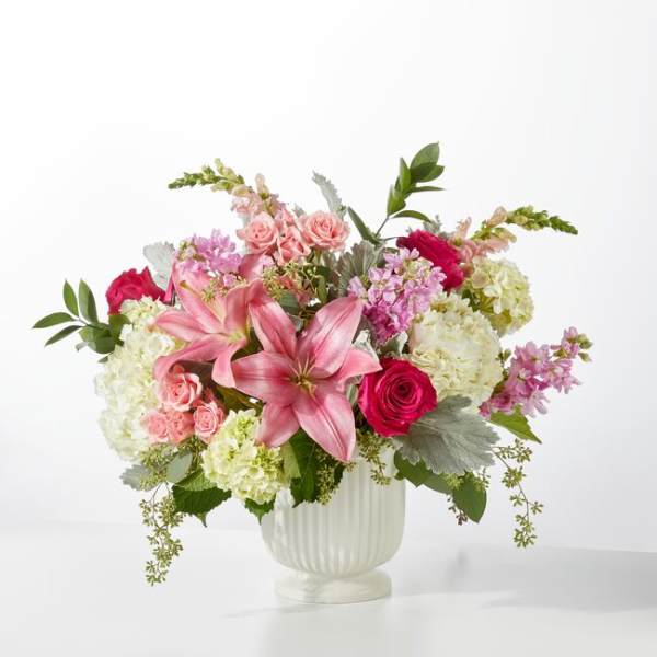Pink lilies and roses arranged in a white vase