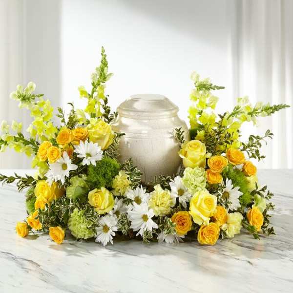 Yellow roses and white daisies arranged around a silver urn