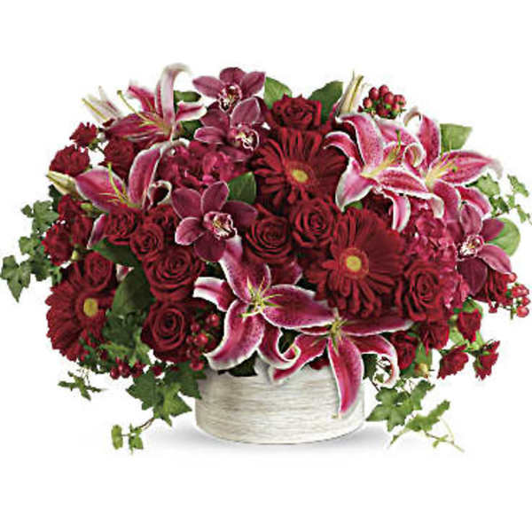 Red and pink mixed flower arrangement in a white vase