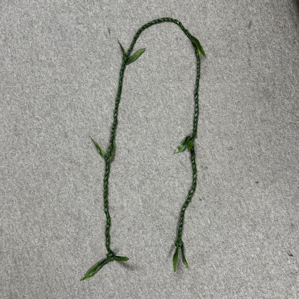 Braided green floral garland on a gray surface