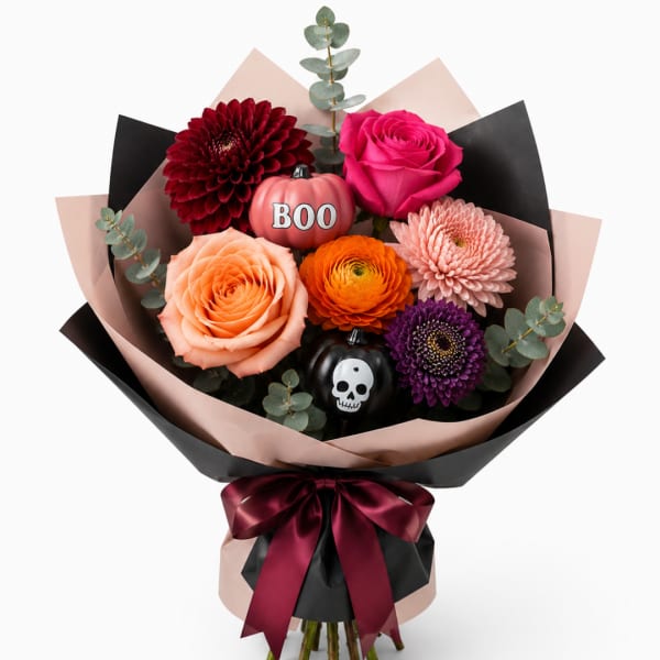 Bouquet of mixed flowers with Halloween pumpkin decorations and a skull ornament