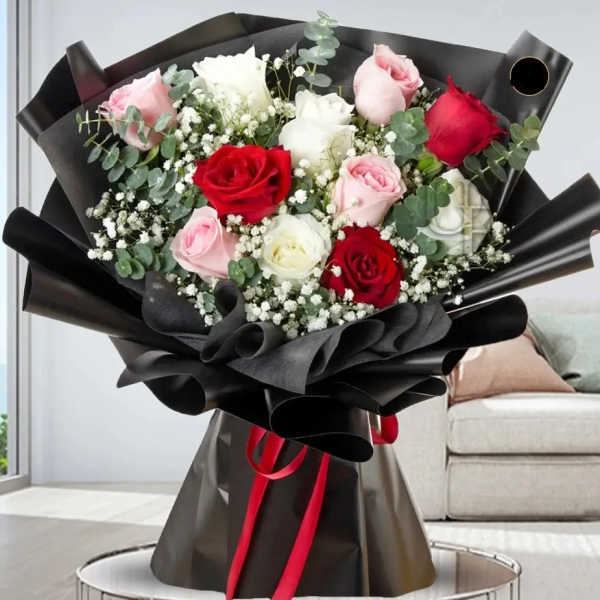 Bouquet of red, pink, and white roses wrapped in black paper