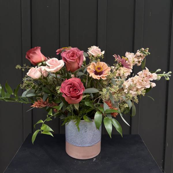 Mixed pink and peach roses in a two-tone ceramic vase
