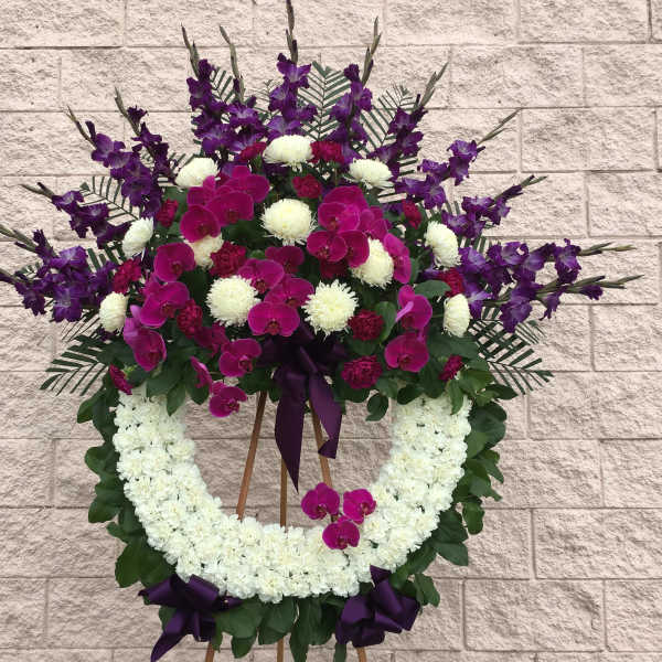 Standing floral wreath with purple orchids and white flowers on an easel
