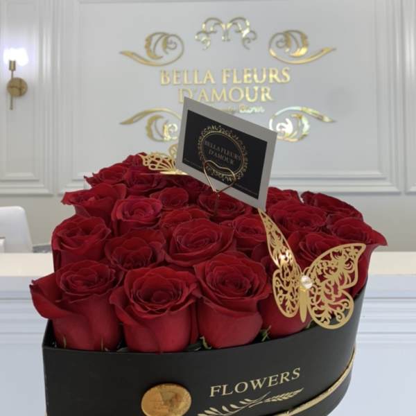 Red roses arranged in a black round box with gold butterfly accents