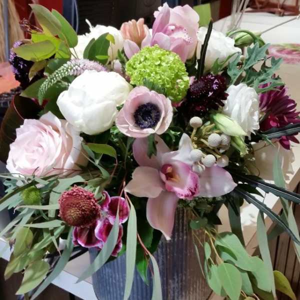 Mixed bouquet of pink, white, and green flowers in a metal vase
