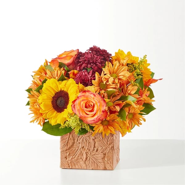 Autumn bouquet with sunflowers, roses, and mums in a textured square vase