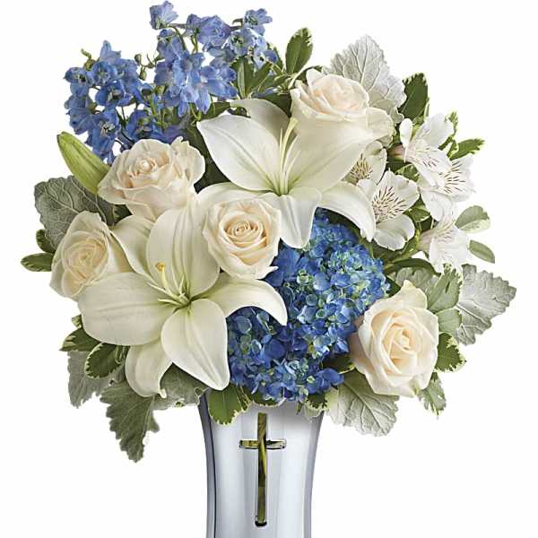 White lilies, cream roses, and blue hydrangeas in a silver vase