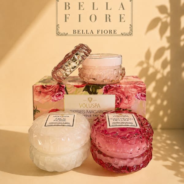 Stacked scented candles in pink and white glass jars with floral packaging