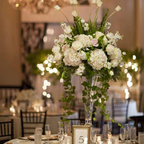 Tall white floral centerpiece in a clear vase on a banquet table