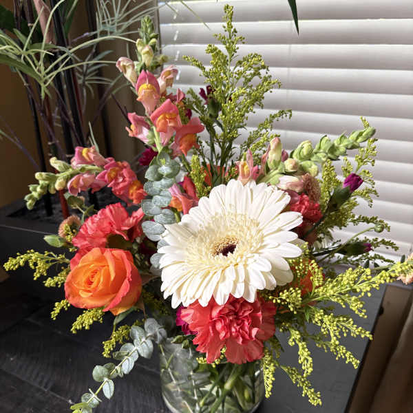 Mixed bouquet in a clear glass vase with a white gerbera and pink-orange blooms