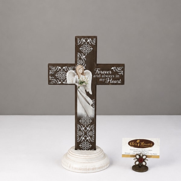Decorative memorial cross with an angel and white flowers on a round base