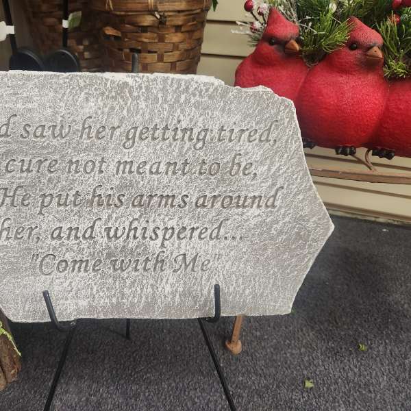 Memorial stone with engraved quote beside red and white roses