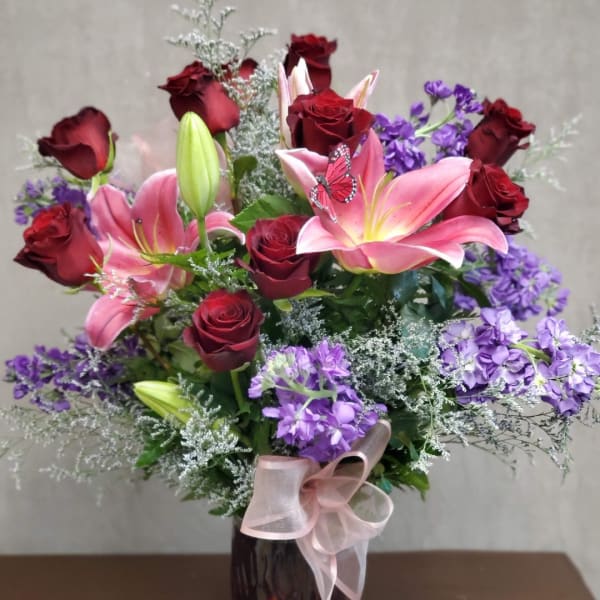 Bouquet of red roses and pink lilies in a vase with a ribbon