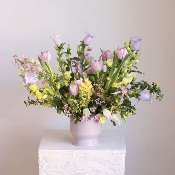 Pastel floral arrangement in a pink vase with tulips and bell-shaped blooms