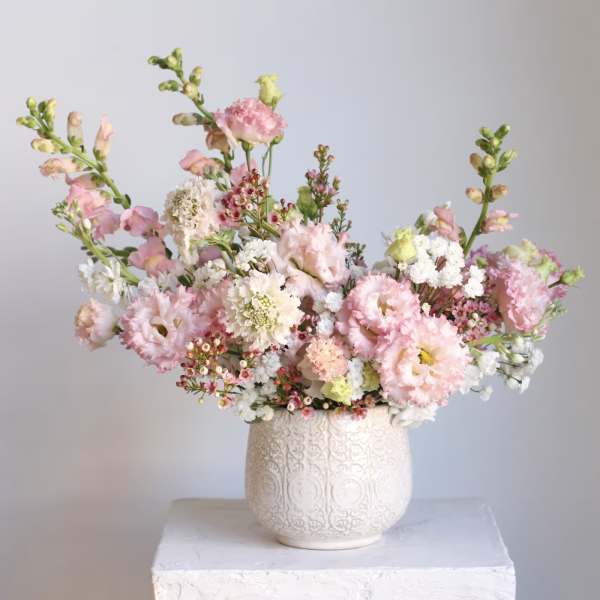 Pink and white floral arrangement in a patterned white vase
