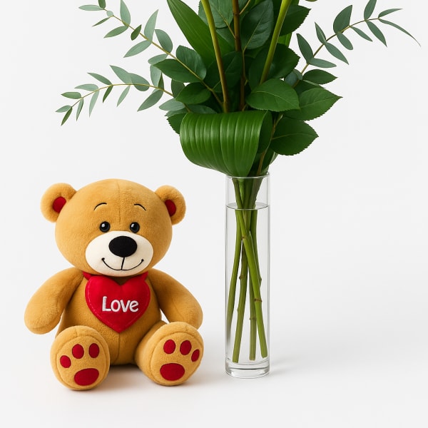 Three red roses in a glass vase beside a teddy bear holding a heart