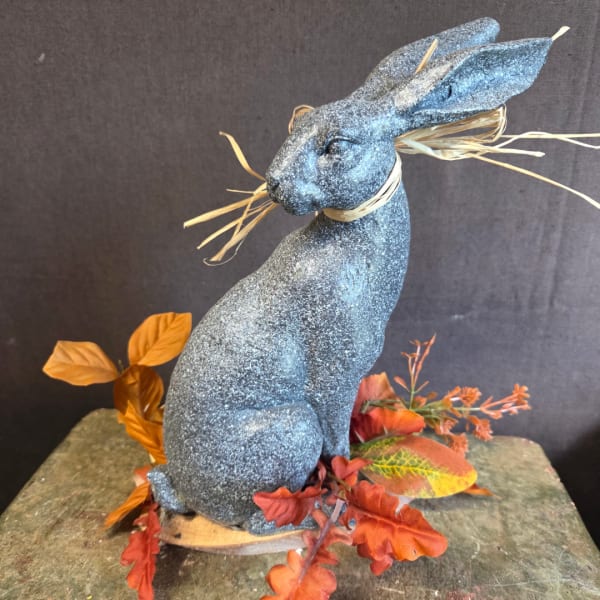 Blue glitter rabbit figurine with autumn leaves on a stone base