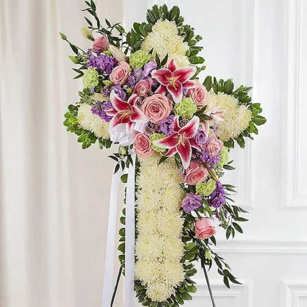 Standing floral cross with pink roses and lilies on an easel