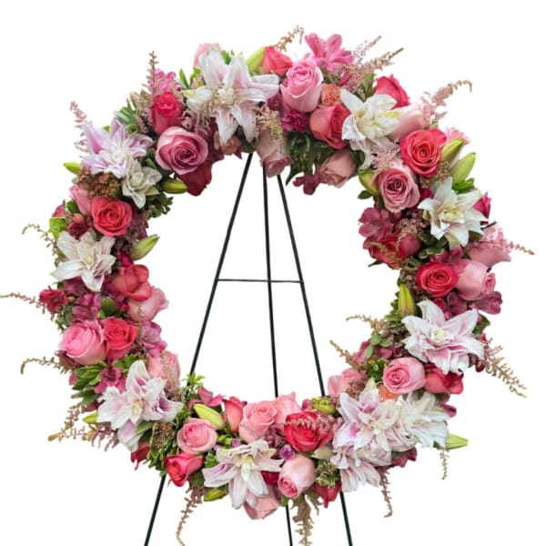 Pink and white floral wreath on a black stand