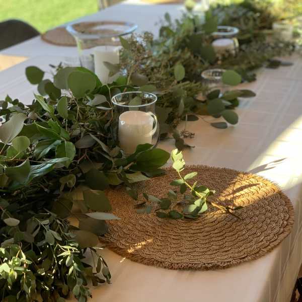 Greenery garland with glass candle holders on a white table