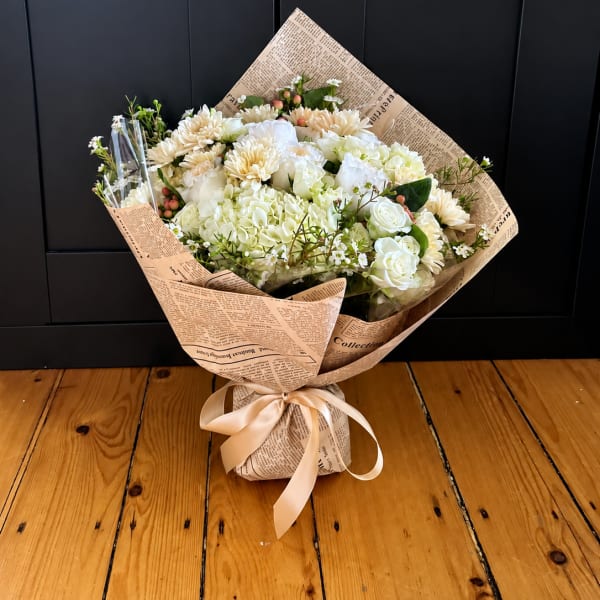 Wrapped bouquet of white and cream flowers tied with a satin ribbon