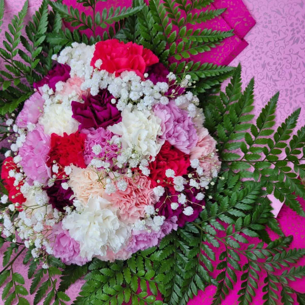 Round bouquet of pink, white, and red carnations with fern foliage