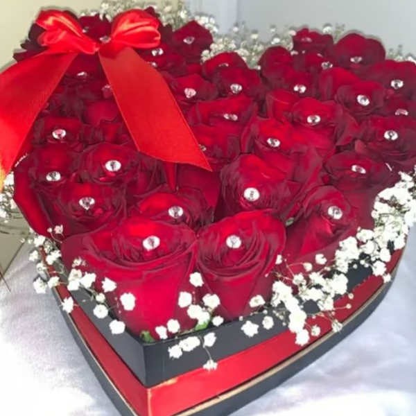Heart-shaped box filled with red roses and a red ribbon bow