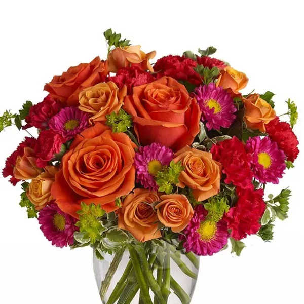 Orange roses and magenta daisies in a clear glass vase