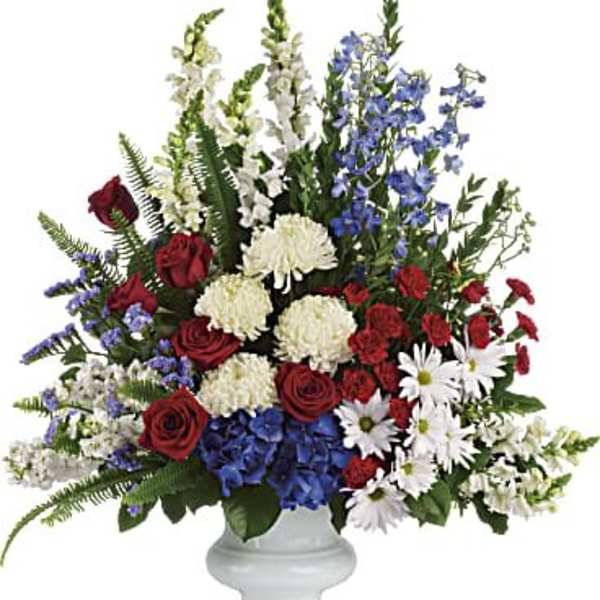 Large mixed flower arrangement in a white pedestal vase