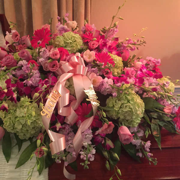 Large pink and green floral casket spray with ribbon