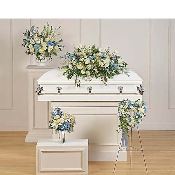 White casket with blue and cream floral sprays in a funeral room