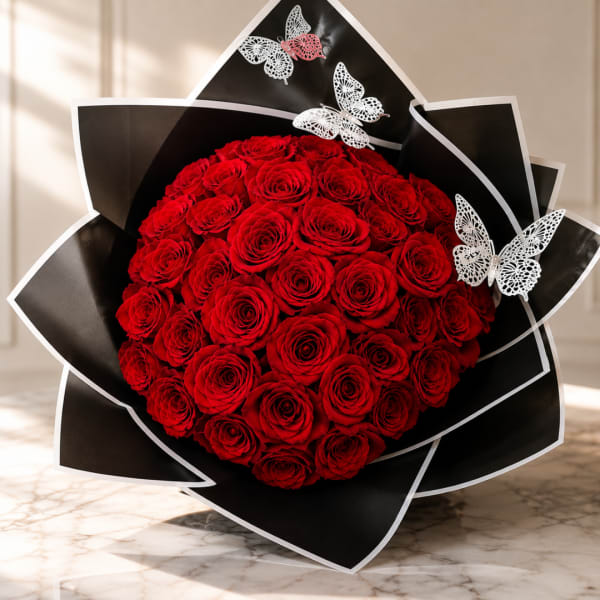 Round bouquet of red roses wrapped in black paper with butterfly accents