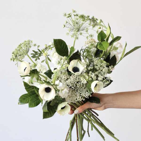 Handheld bouquet of white anemones and airy white filler flowers