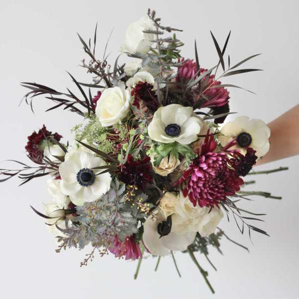 Bouquet of white anemones and magenta blooms with dark foliage