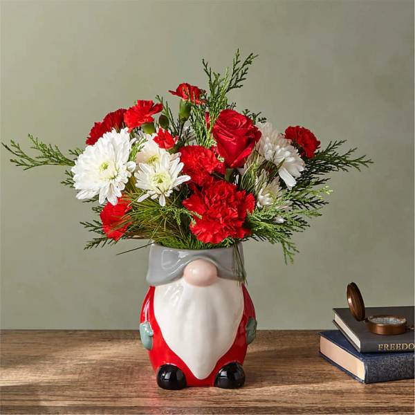 Red and white flowers arranged in a Santa-shaped vase