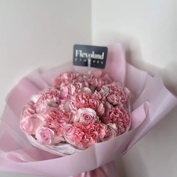 Pink bouquet of roses and carnations wrapped in pale pink paper