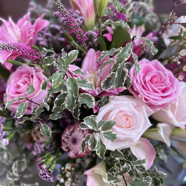 Pink roses and lilies in a mixed bouquet with variegated foliage