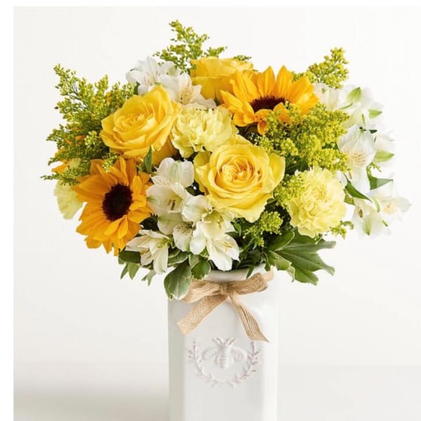 Yellow roses and sunflowers in a white vase with a burlap bow