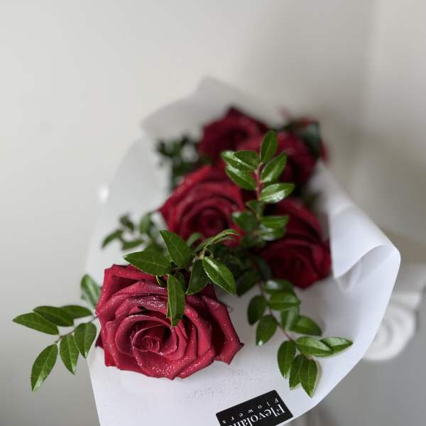 Bouquet of deep pink roses with green foliage in white wrap